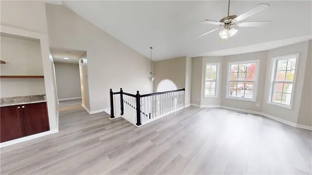 wooden floor in an empty room with a window and a kitchen