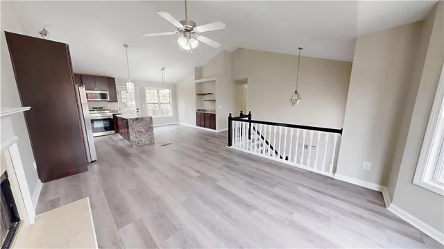 a view of a livingroom with furniture a fireplace a ceiling fan and wooden floor