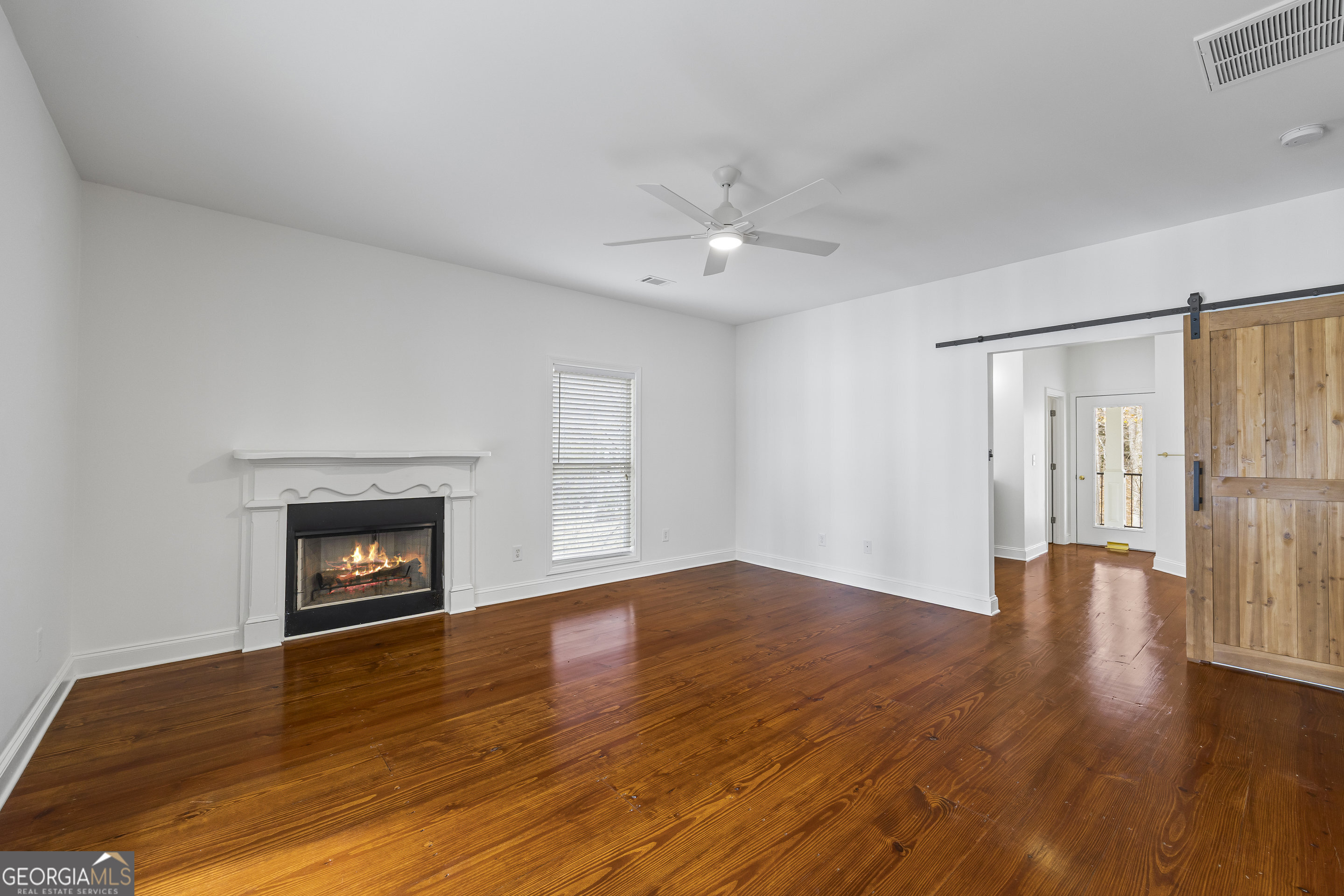 1270 Swords Road Greensboro, GA 30642 - Photo 30 of 44 an empty room with wooden floor fireplace and windows