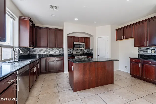 a kitchen with stainless steel appliances kitchen island granite countertop a refrigerator and a sink