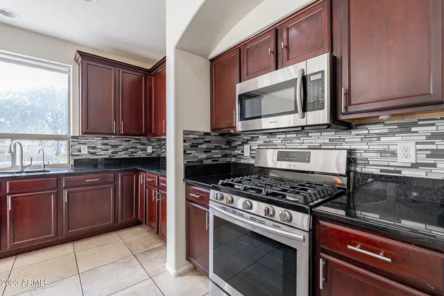 a kitchen with stainless steel appliances granite countertop a stove a sink and a refrigerator