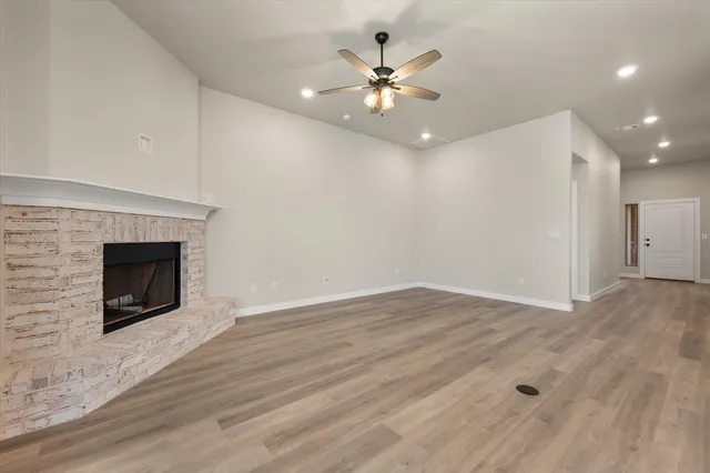 a view of an empty room with wooden floor and a fireplace
