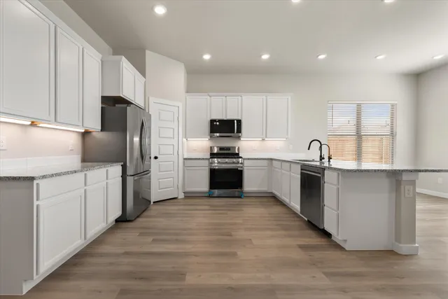 a kitchen with granite countertop a refrigerator and a stove top oven