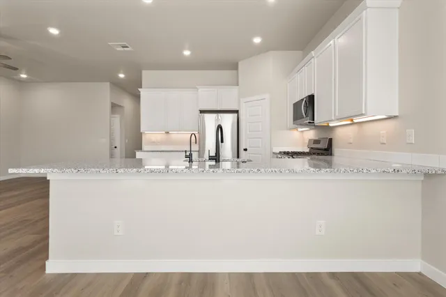 a kitchen with stainless steel appliances granite countertop a stove a sink and a refrigerator