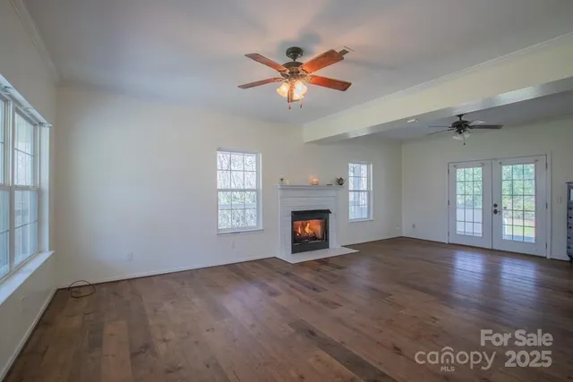 an empty room with wooden floor fan and windows