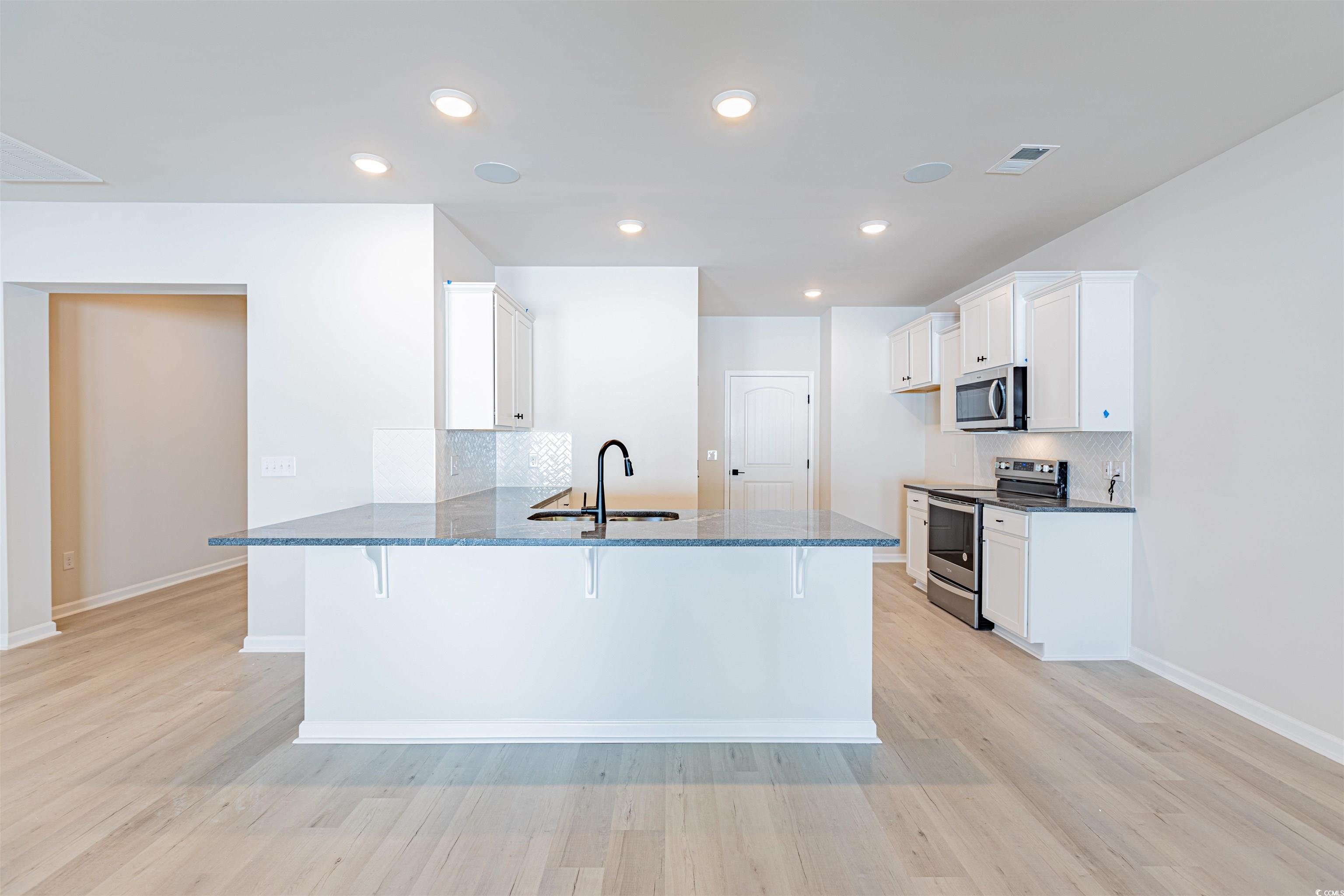 556 Honeyhill Loop Conway, SC 29526 - Photo 25 of 40 Kitchen with a kitchen bar, a sink, dark stone cou