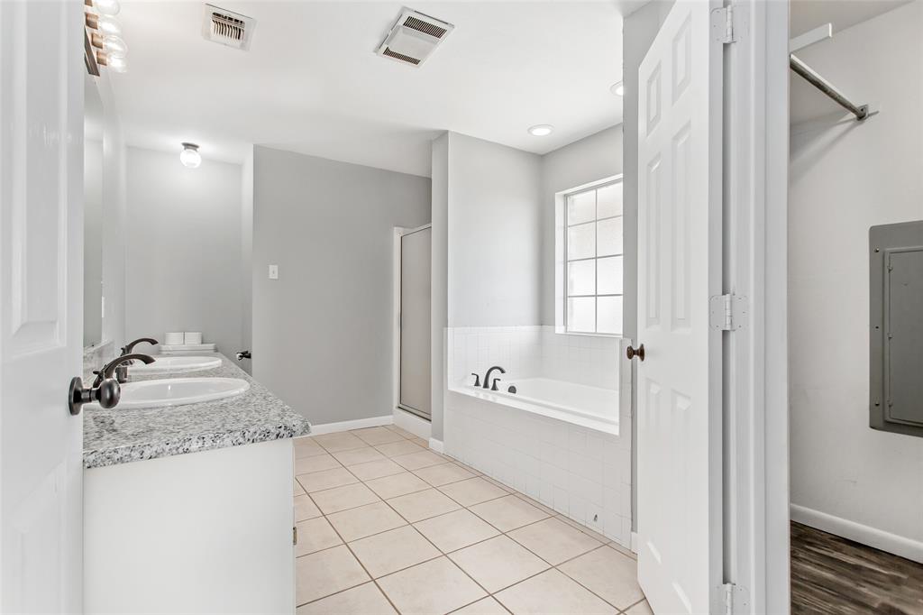 712 Billups Street Van Alstyne, TX 75495 - Photo 23 of 38 a spacious bathroom with a granite countertop sink a mirror and a bathtub