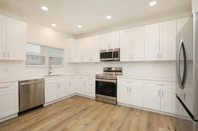 a kitchen with stainless steel appliances granite countertop a stove a sink and a refrigerator