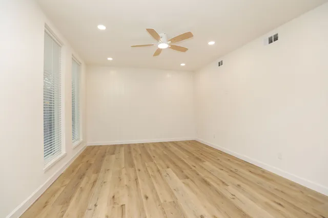 an empty room with wooden floor and windows