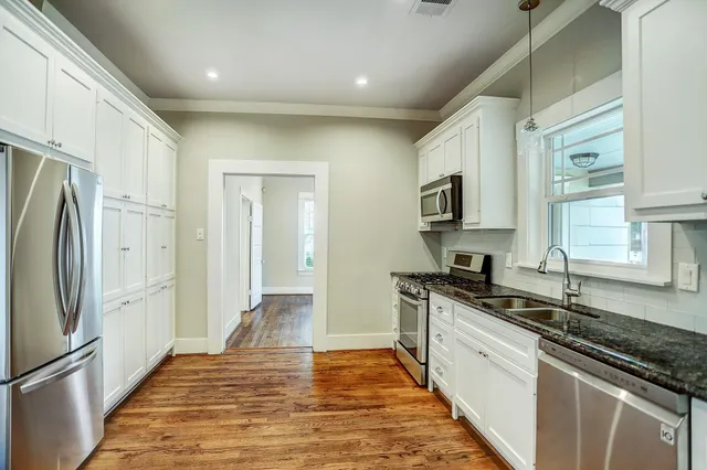a kitchen with granite countertop a refrigerator stove and sink