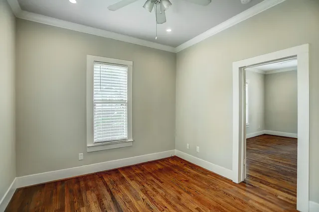an empty room with wooden floor cabinet and windows