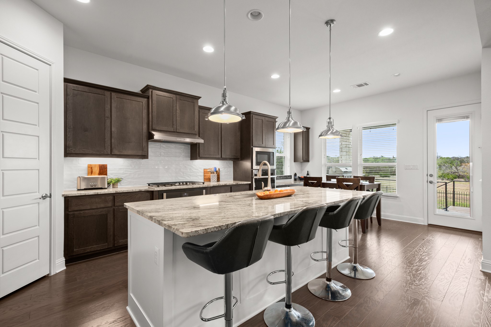 330 Cistern Way Austin, TX 78737 - Photo 9 of 40 a kitchen with stainless steel appliances granite countertop a stove top oven a refrigerator a sink and a island with wooden floor