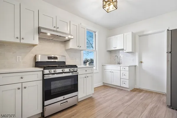 a kitchen with cabinets stainless steel appliances and wooden floor