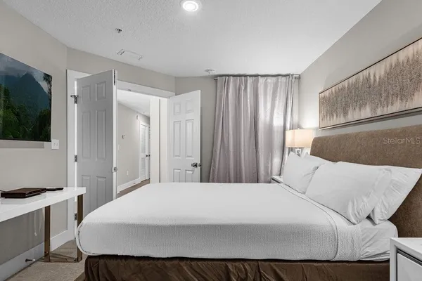 a bedroom with a large bed and a flat tv screen