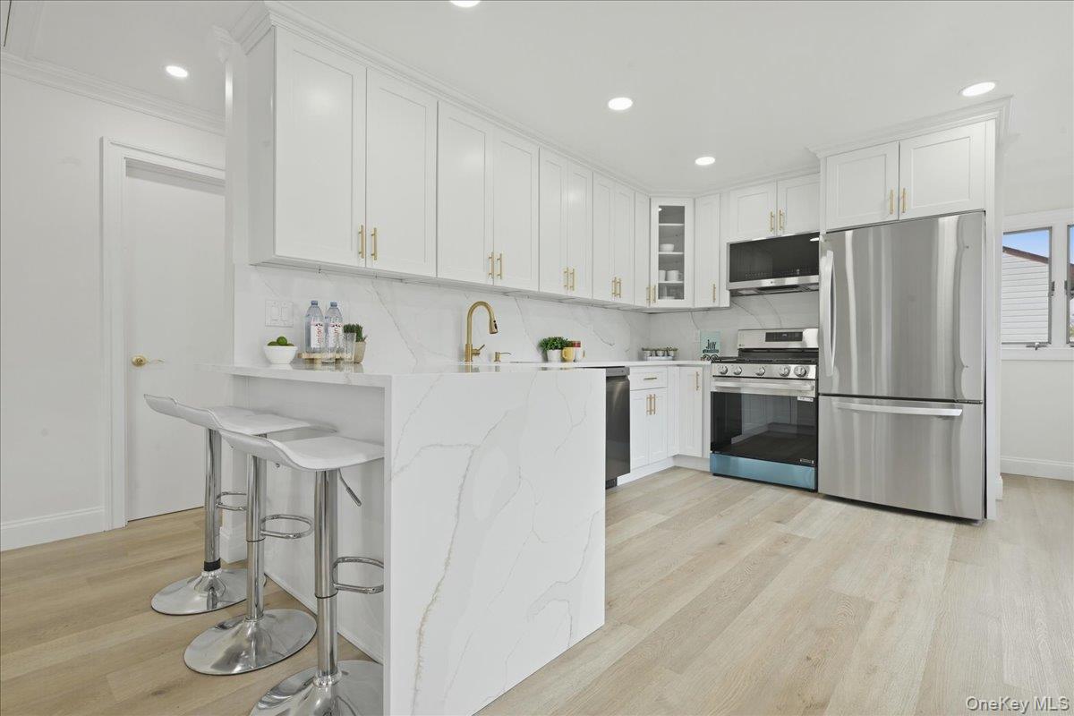 84 North Fordham Road Hicksville, NY 11801 - Photo 5 of 28 a kitchen with stainless steel appliances granite countertop a sink a stove a refrigerator and white cabinets with wooden floor