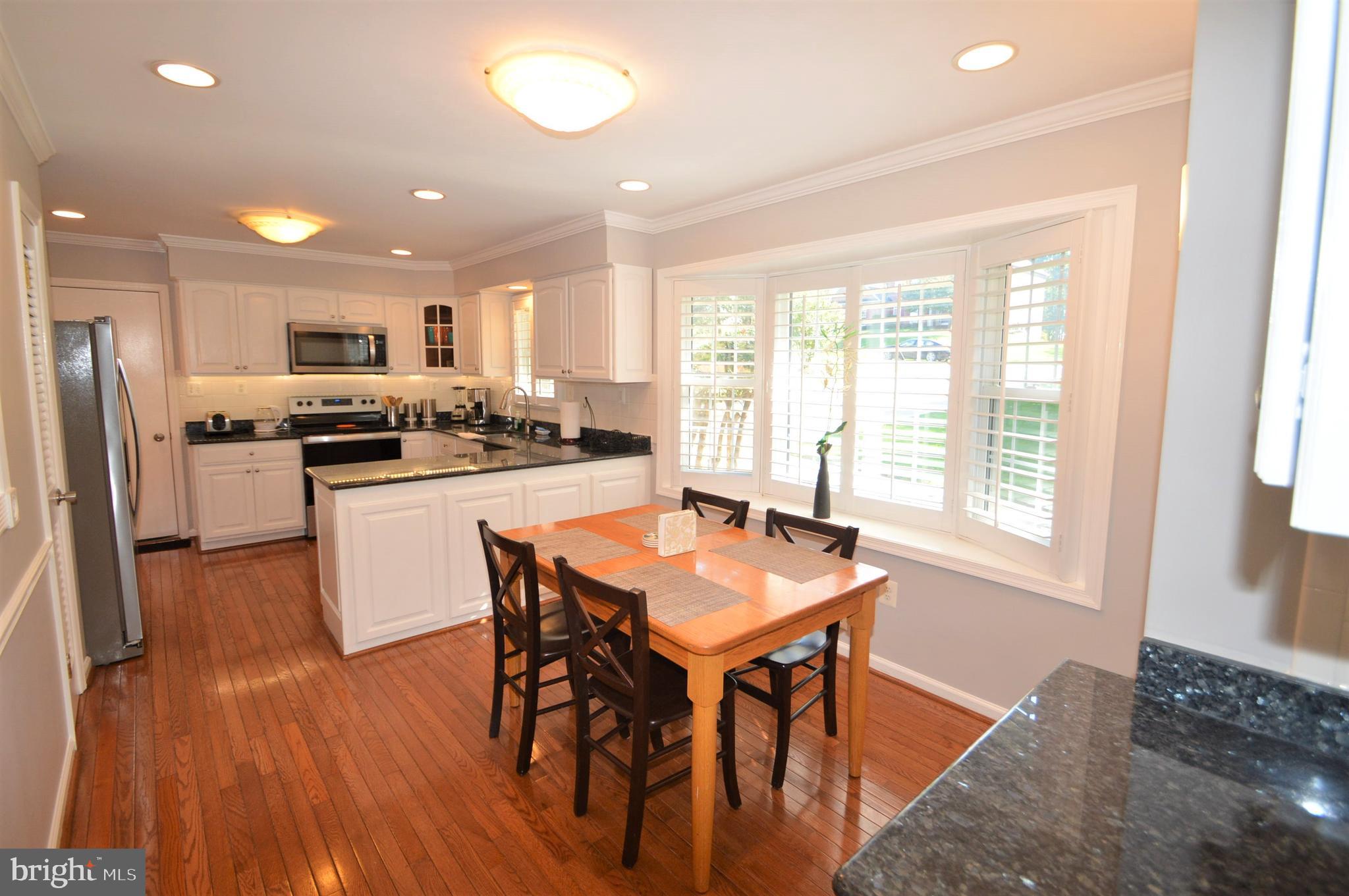 12614 Oxon Road Herndon, VA 20171 - Photo 25 of 71 a kitchen with stainless steel appliances granite countertop a stove a refrigerator a sink a dining table and chairs with wooden floor