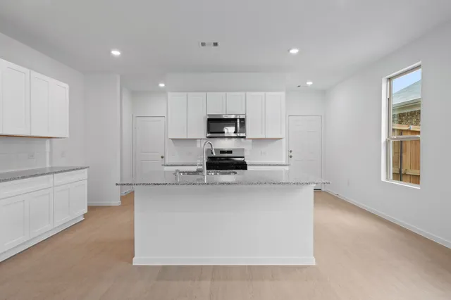 a kitchen with kitchen island white cabinets appliances and a window