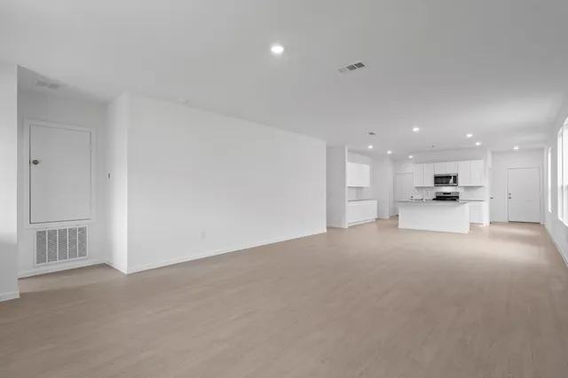 a view of an empty room and a kitchen