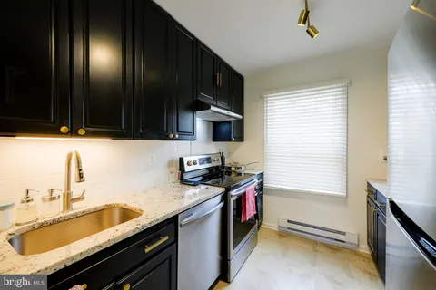 a kitchen with granite countertop stainless steel appliances a sink stove top oven and cabinets