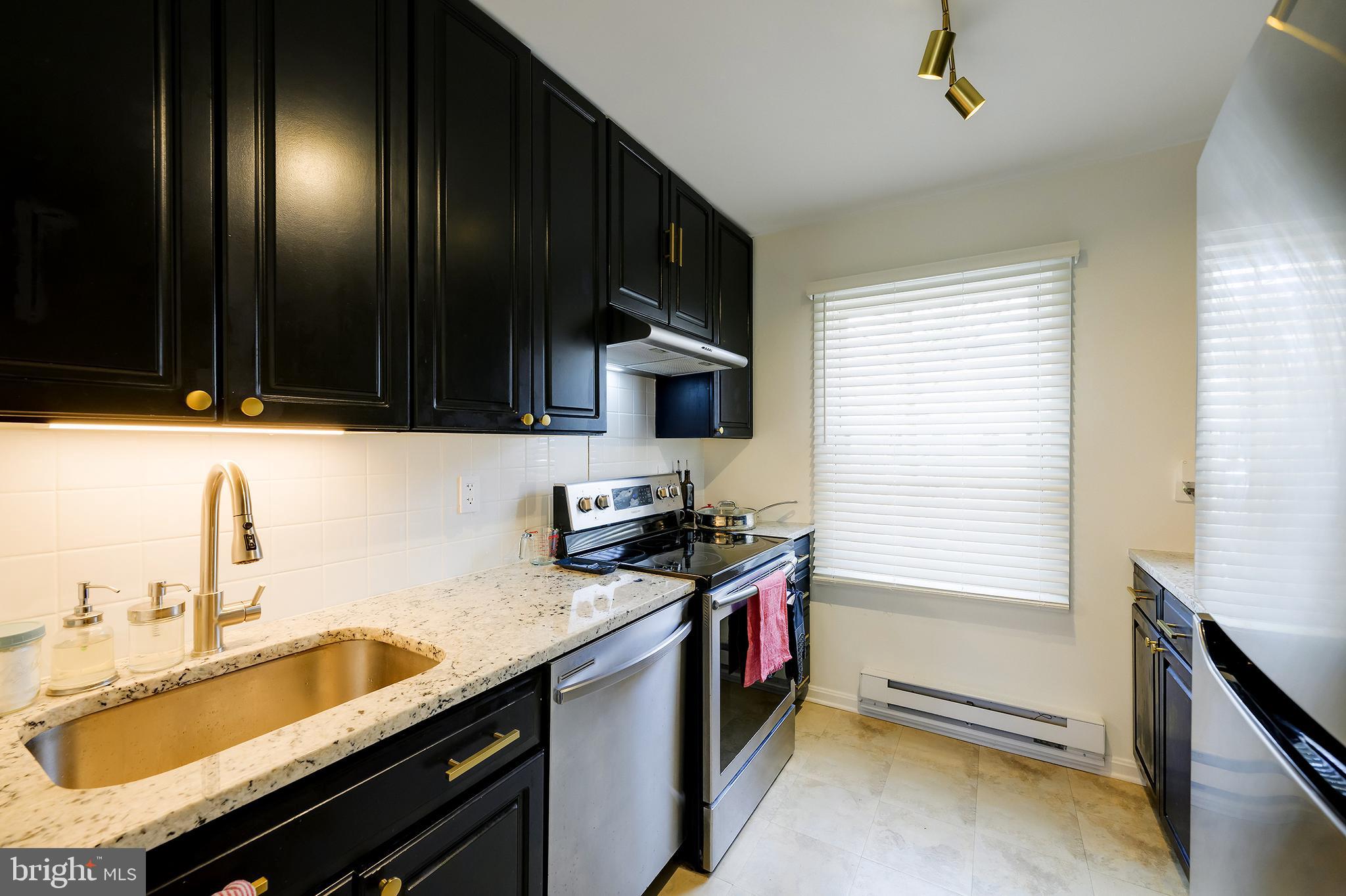 14 Laurel Hill Road Greenbelt, MD 20770 - Photo 15 of 41 a kitchen with granite countertop stainless steel appliances a sink stove top oven and cabinets