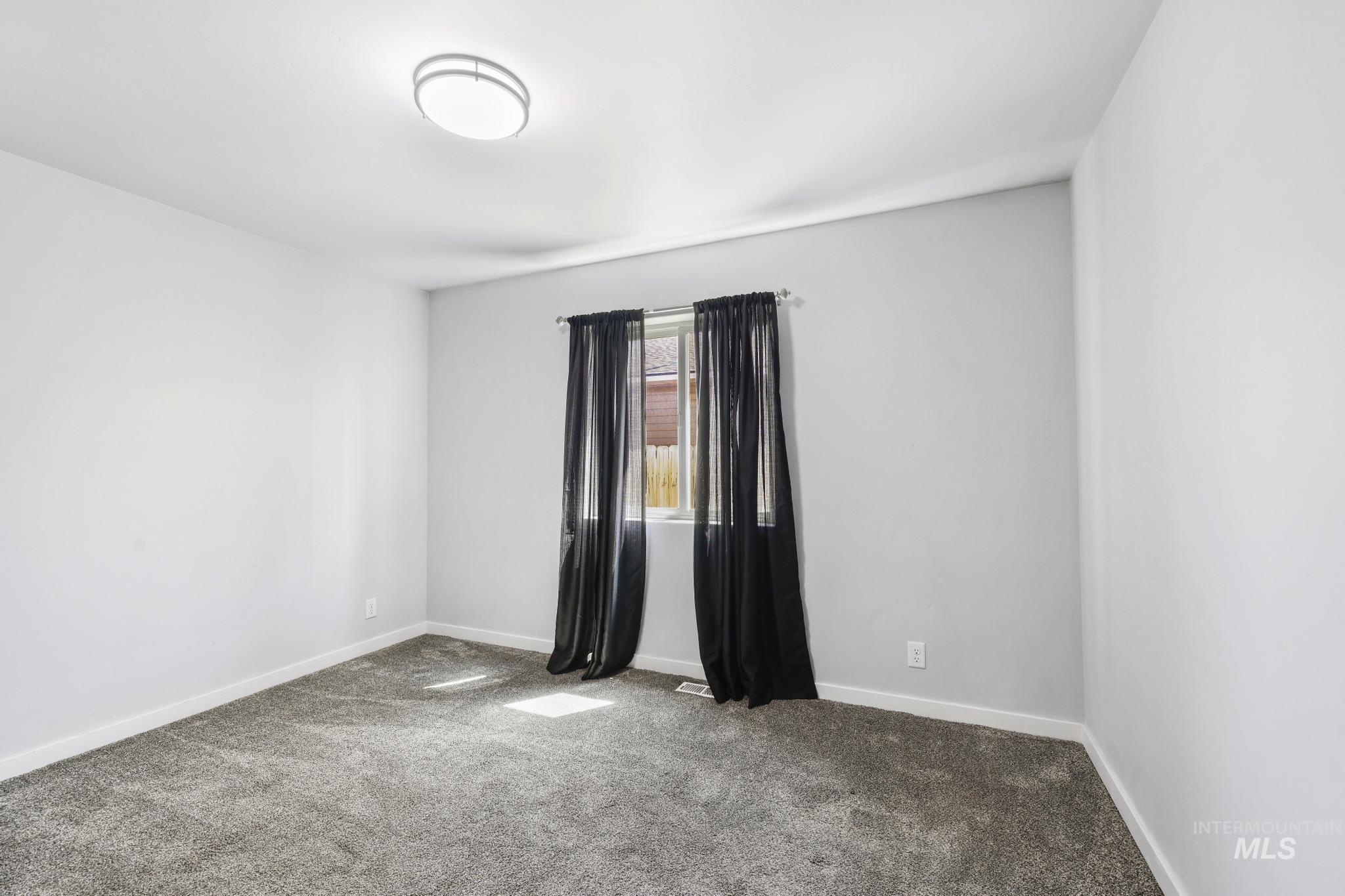 826 Normal Burley, ID 83318 - Photo 11 of 21 Carpeted room featuring a window with installed curtain rod, white baseboards, and a flush-mount ceiling light fixture