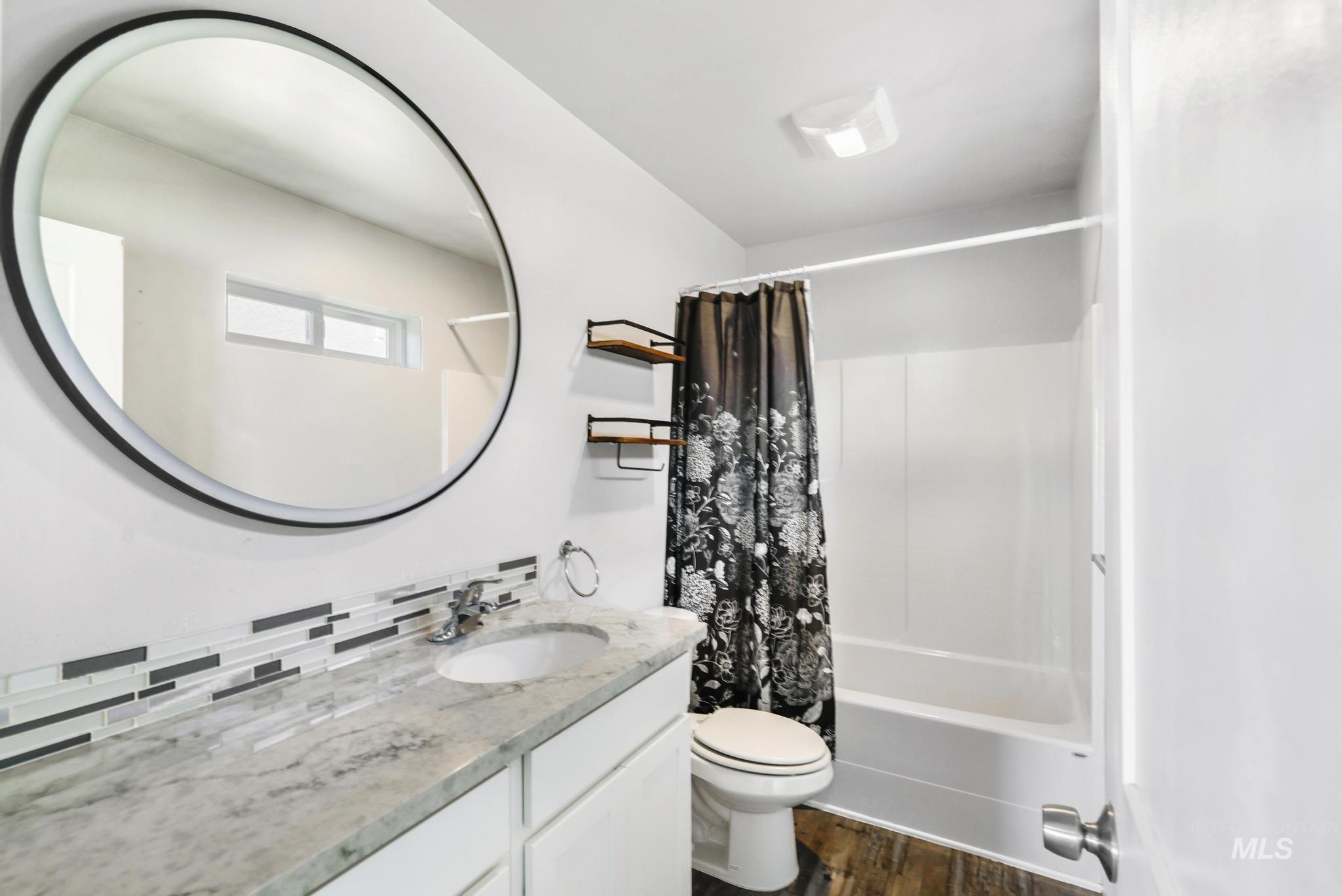 826 Normal Burley, ID 83318 - Photo 18 of 21 Bathroom featuring a built-in vanity with a stone-finish countertop, undermount sink, and a multi-tone tile backsplash