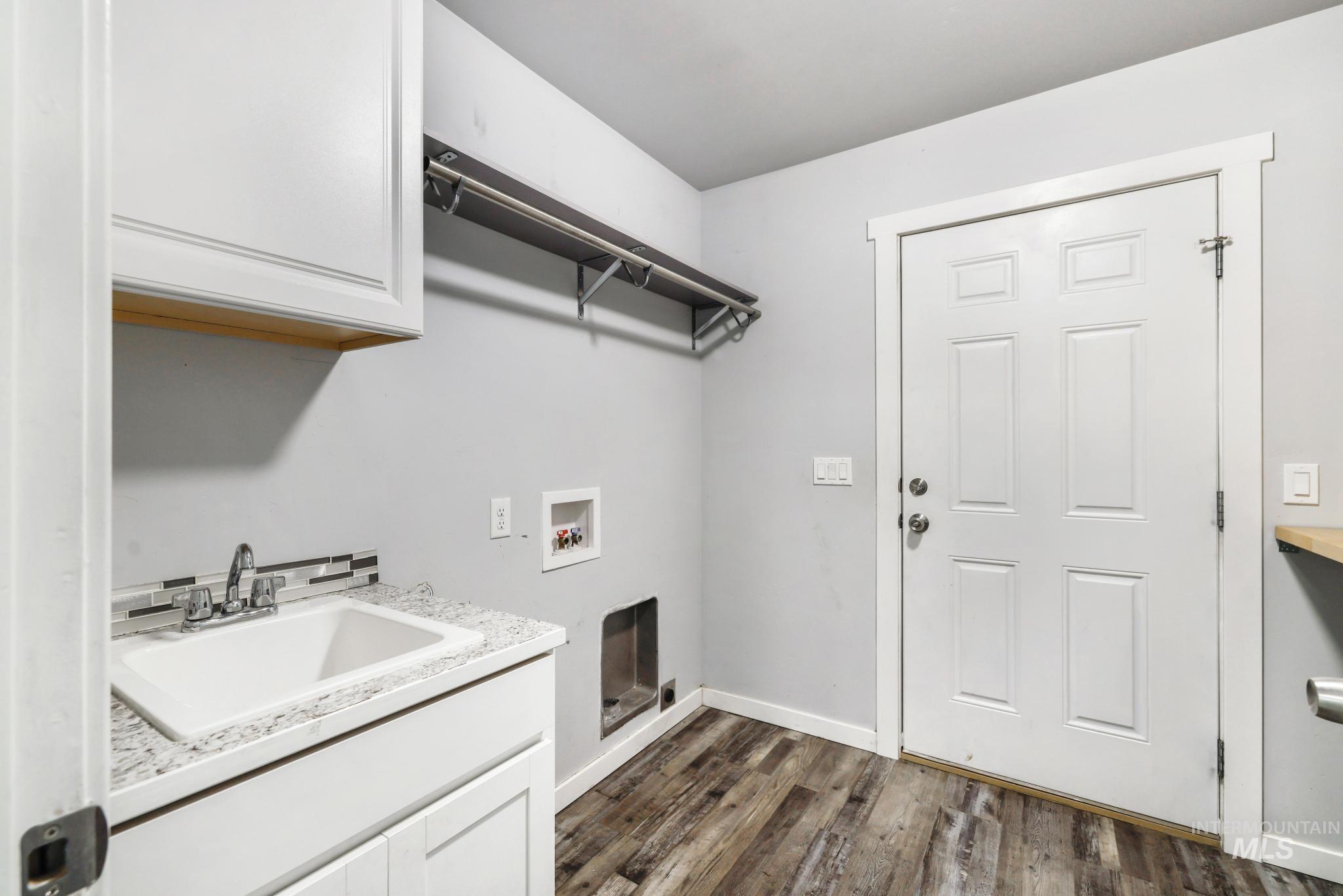 826 Normal Burley, ID 83318 - Photo 19 of 21 Utility room featuring wood-finish flooring, a laundry sink with a white basin, a light-toned speckled countertop, and a white paneled door