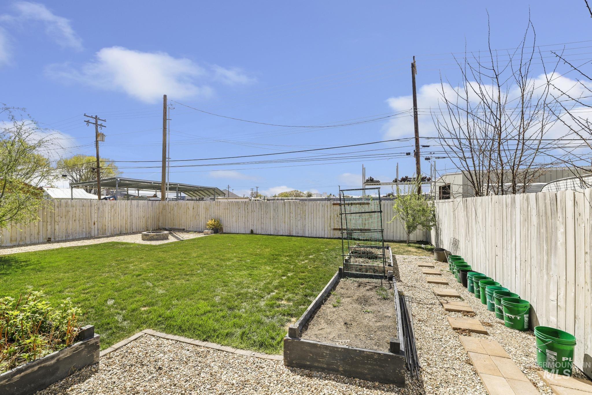 826 Normal Burley, ID 83318 - Photo 21 of 21 Expansive backyard featuring a lush lawn, privacy fencing, a fire pit, raised garden beds, and a paver stone walkway