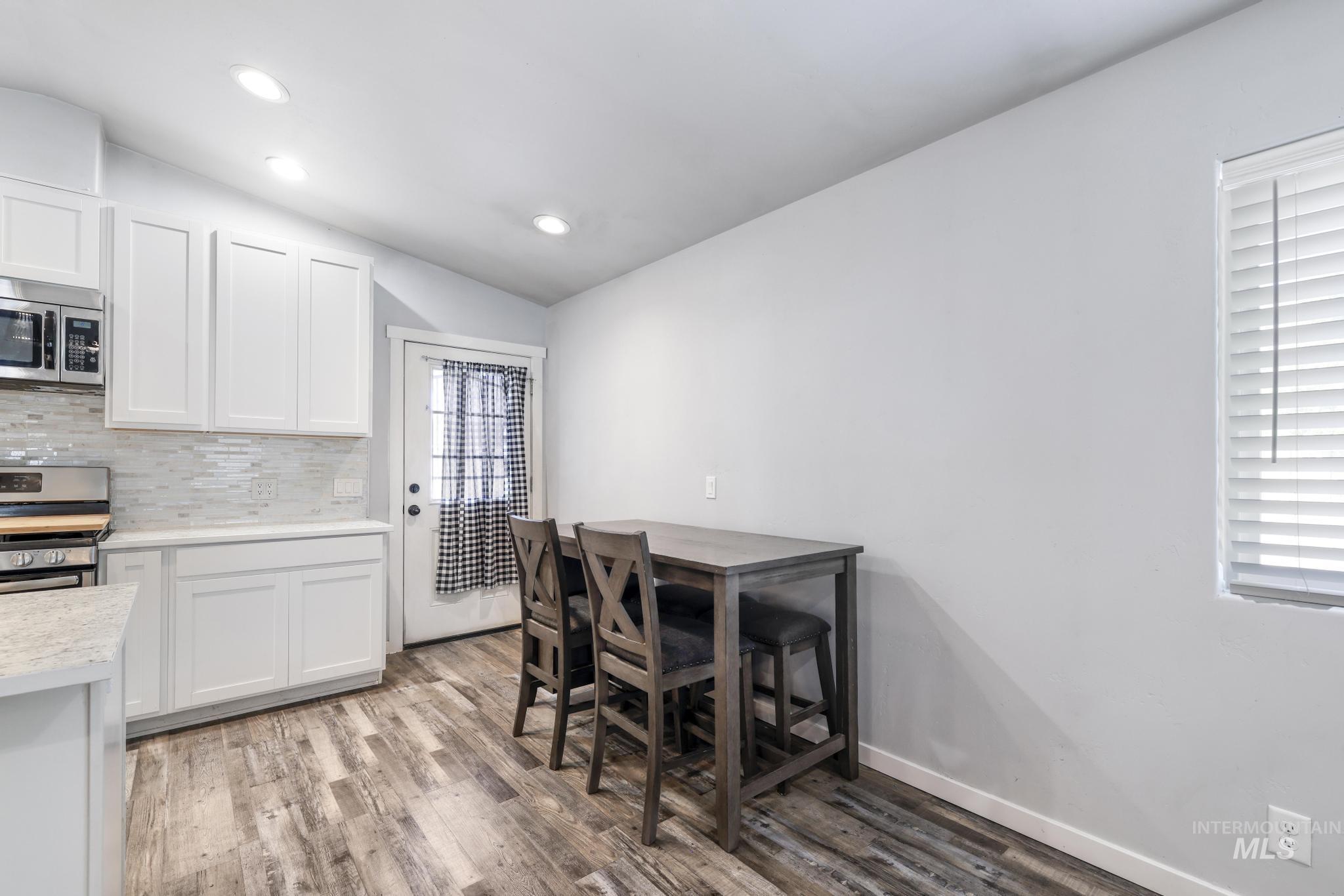 826 Normal Burley, ID 83318 - Photo 6 of 21 Modern kitchen featuring white shaker cabinetry, stainless steel appliances, a light-toned backsplash, and wood-finish flooring