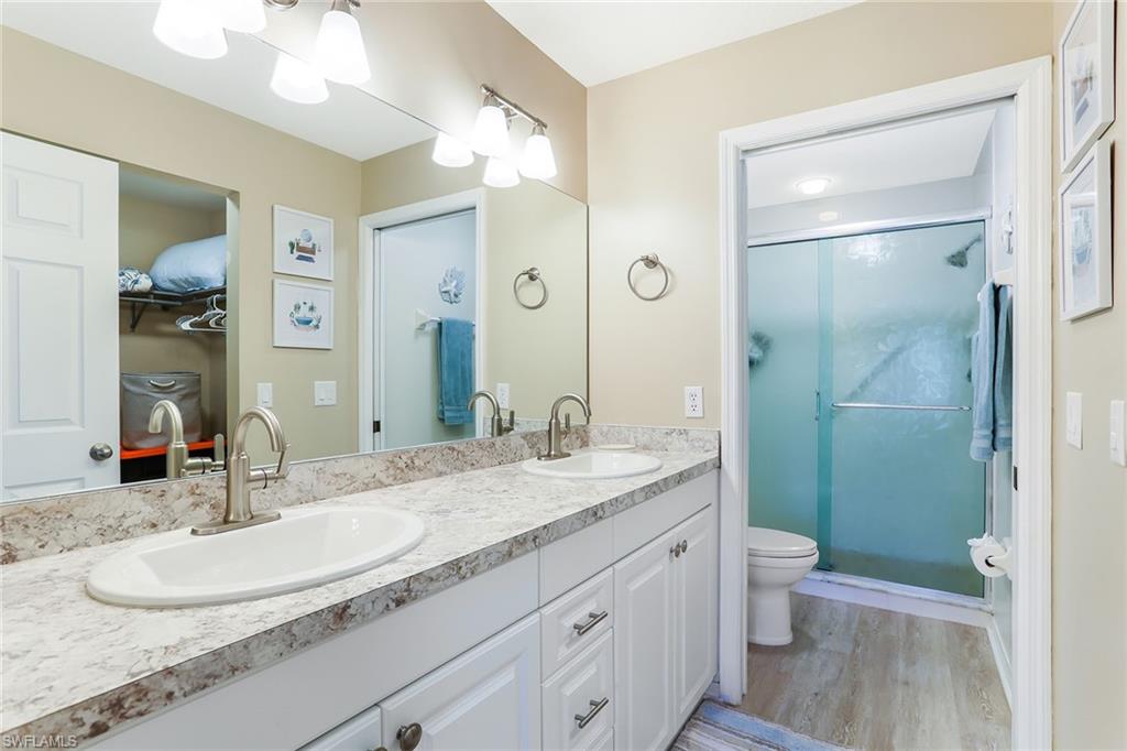 9022 Michael Circle, Unit 4 Naples, FL 34113 - Photo 18 of 28 a bathroom with a granite countertop sink a toilet and a large mirror