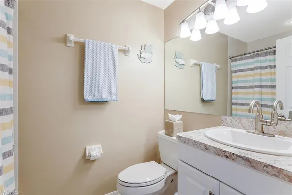 a bathroom with a granite countertop sink a toilet and a mirror