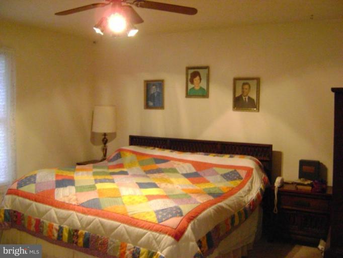 17868 Piney Point Road Tall Timbers, MD 20690 - Photo 4 of 13 a bed sitting in a bedroom next to a lamp