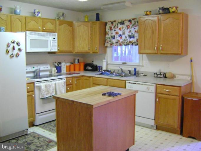 17868 Piney Point Road Tall Timbers, MD 20690 - Photo 10 of 13 a kitchen with stainless steel appliances a sink a stove a refrigerator cabinets and a counter top space