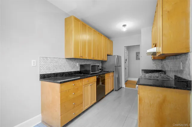 a kitchen with stainless steel appliances granite countertop a stove a sink a refrigerator with grey cabinets