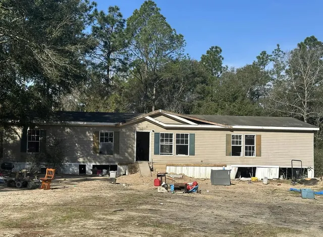 a front view of a house with a large tree in front of house