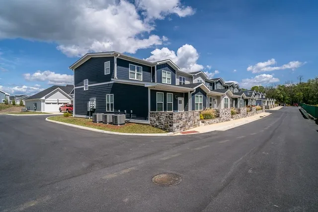 a front view of a house with yard and large trees