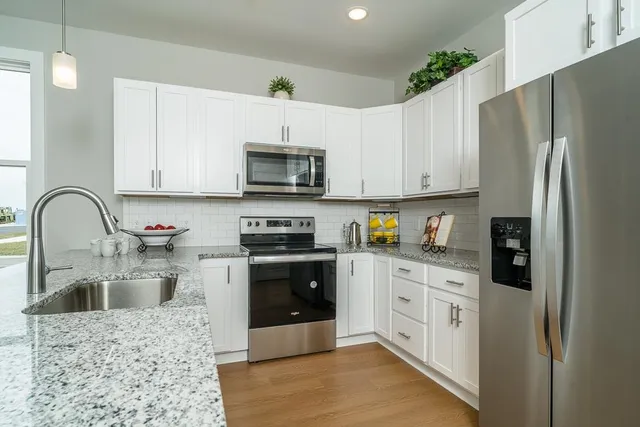 a kitchen with stainless steel appliances granite countertop a refrigerator a stove a sink and a microwave