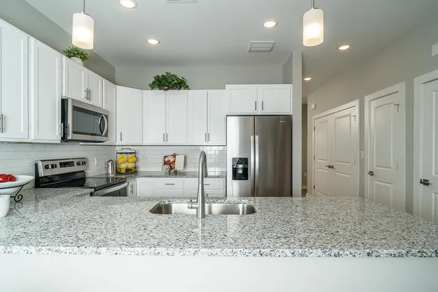 a kitchen with stainless steel appliances granite countertop a refrigerator a stove a sink and a microwave