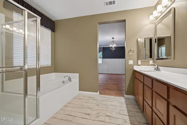 a bathroom with a tub a sink and a large mirror