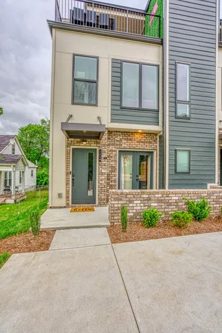 a view of a brick house with plants and large tree
