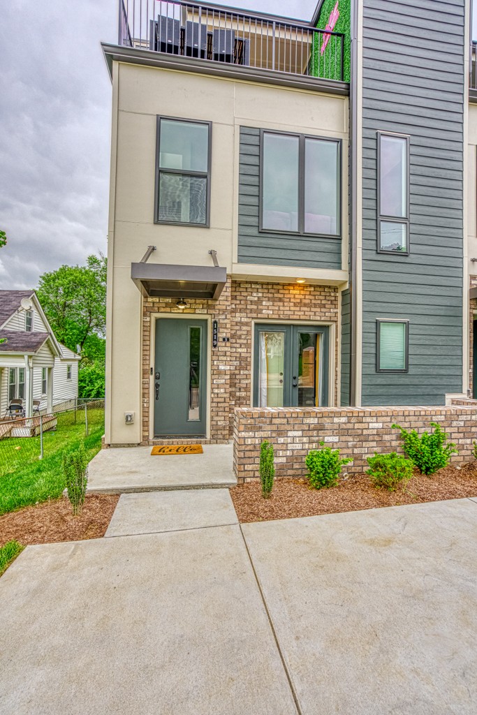 a view of a brick house with plants and large tree