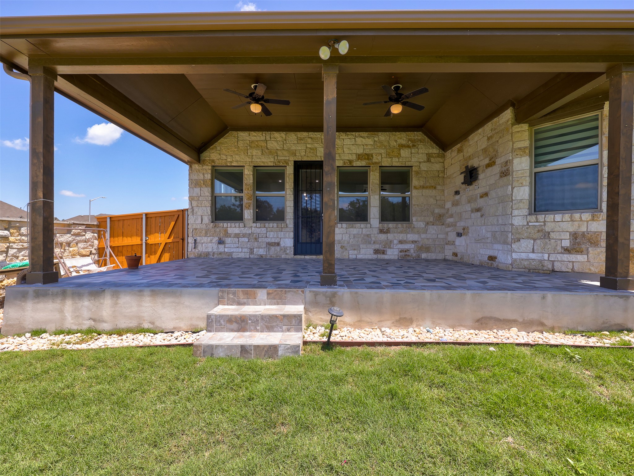 2020 Base Burner Path Leander, TX 78641 - Photo 19 of 22 Doorway to property featuring a ceiling fan, a patio, stone siding, and a yard