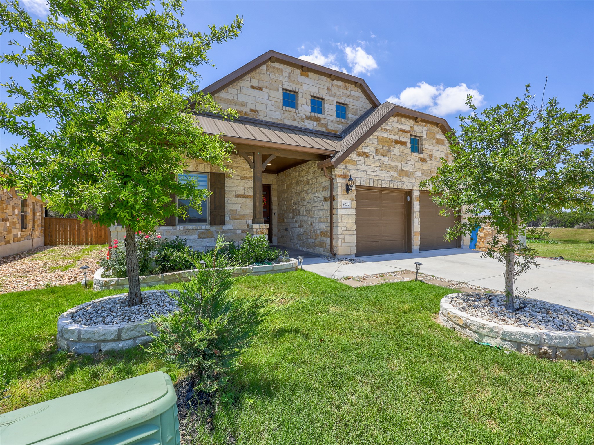 2020 Base Burner Path Leander, TX 78641 - Photo 2 of 22 View of front of property with stone siding, concrete driveway, a metal roof, a standing seam roof, and a garage