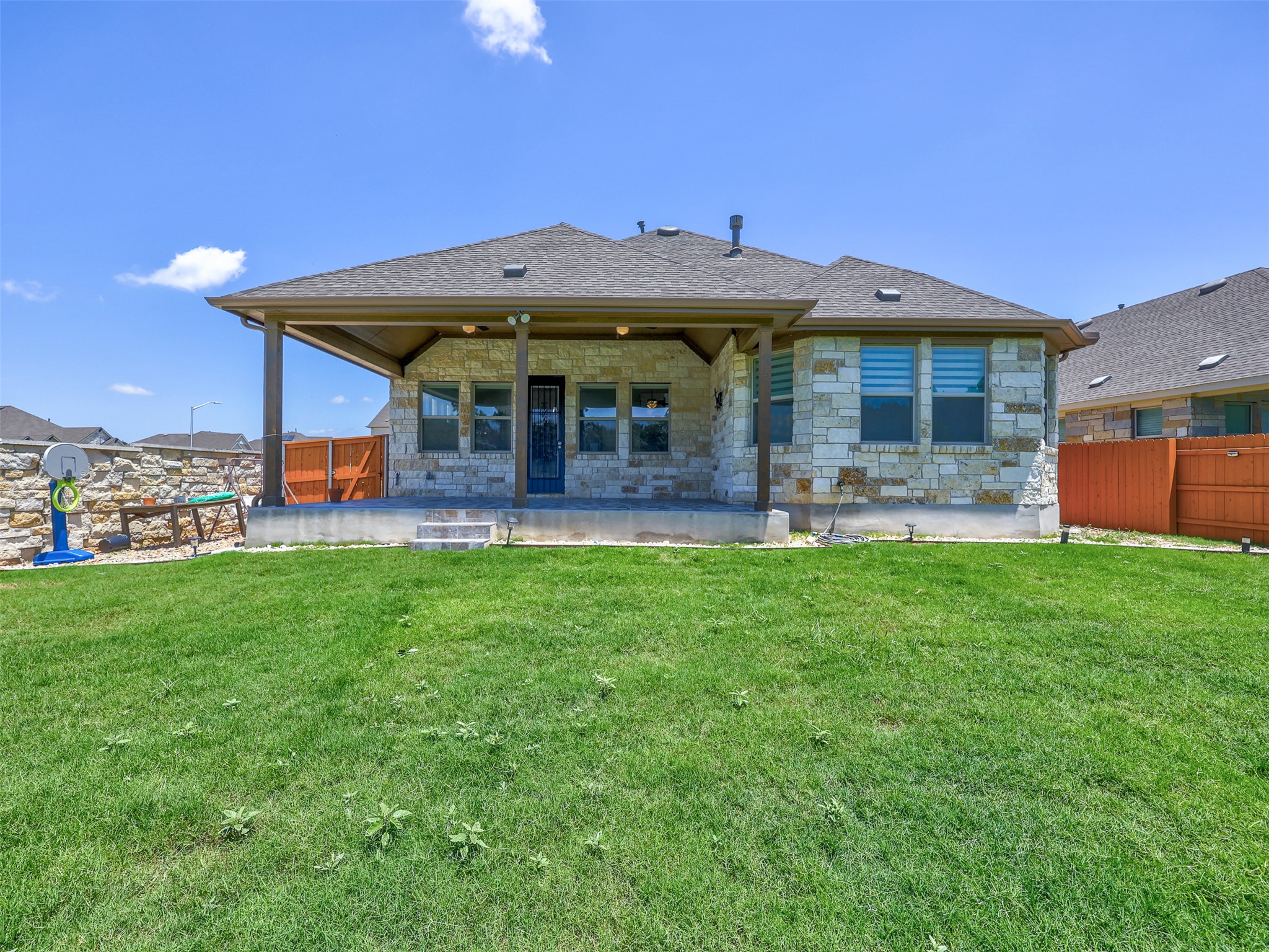 2020 Base Burner Path Leander, TX 78641 - Photo 20 of 22 Back of property featuring stone siding, a patio, and a shingled roof