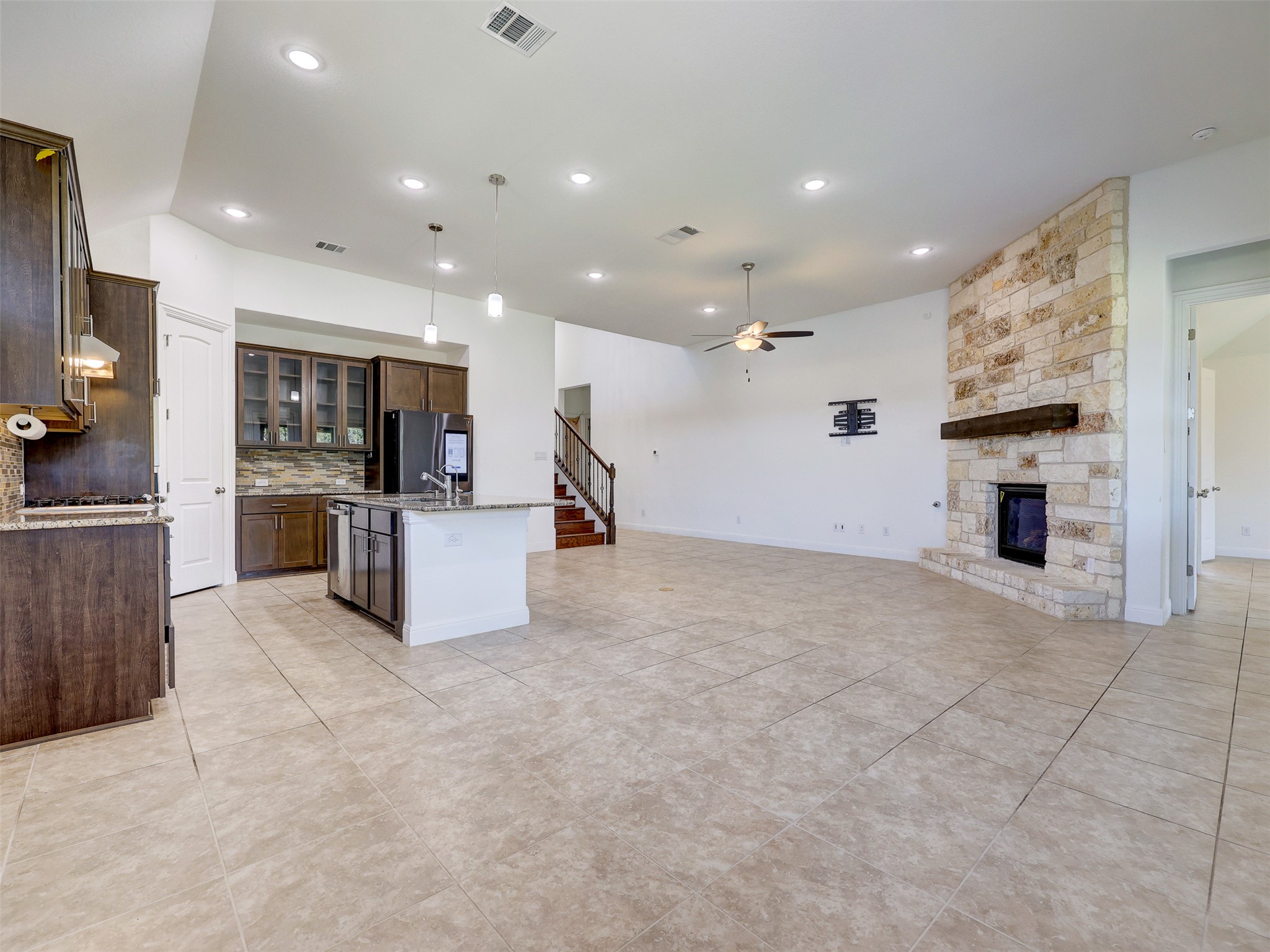 2020 Base Burner Path Leander, TX 78641 - Photo 22 of 22 Kitchen featuring light stone counters, glass insert cabinets, pendant lighting, a stone fireplace, and open floor plan