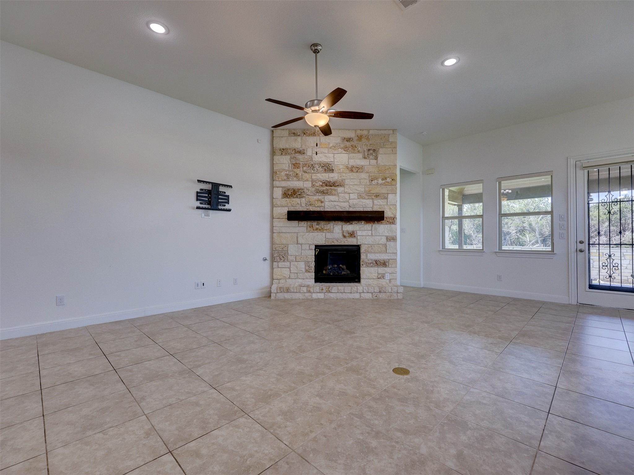 2020 Base Burner Path Leander, TX 78641 - Photo 8 of 22 Unfurnished living room featuring a fireplace, a ceiling fan, light tile patterned floors, and recessed lighting