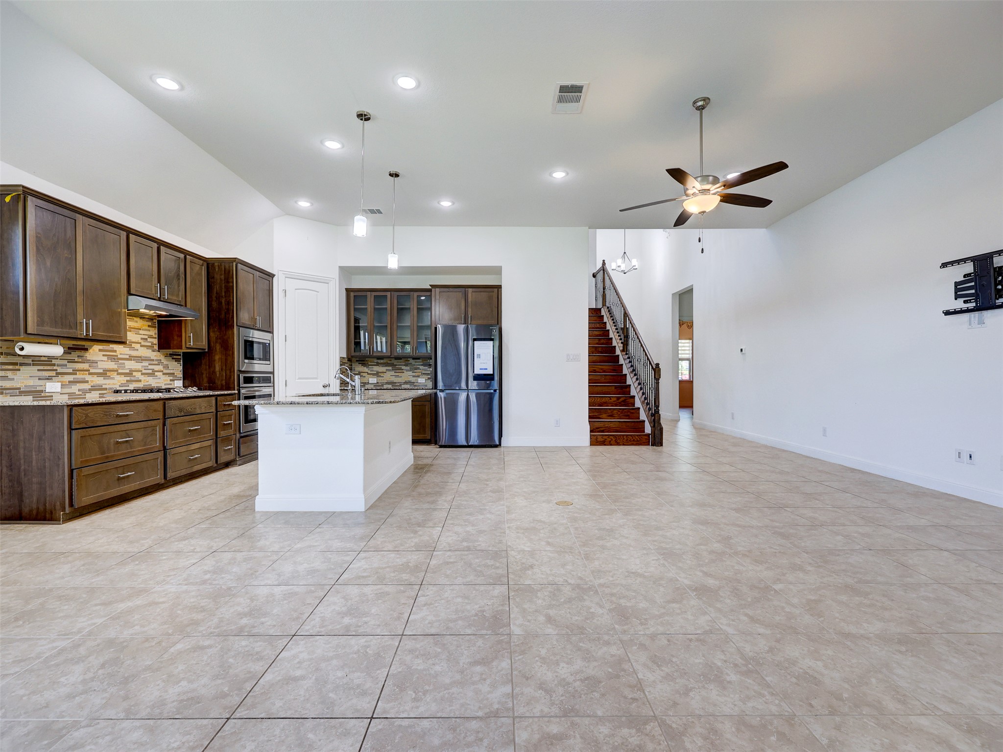 2020 Base Burner Path Leander, TX 78641 - Photo 9 of 22 Kitchen with a kitchen island with sink, appliances with stainless steel finishes, light stone countertops, glass insert cabinets, and pendant lighting