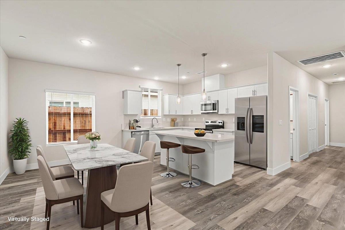 1415 Villa Way Modesto, CA 95351 - Photo 14 of 37 a kitchen with a dining table chairs wooden floor appliances and living room