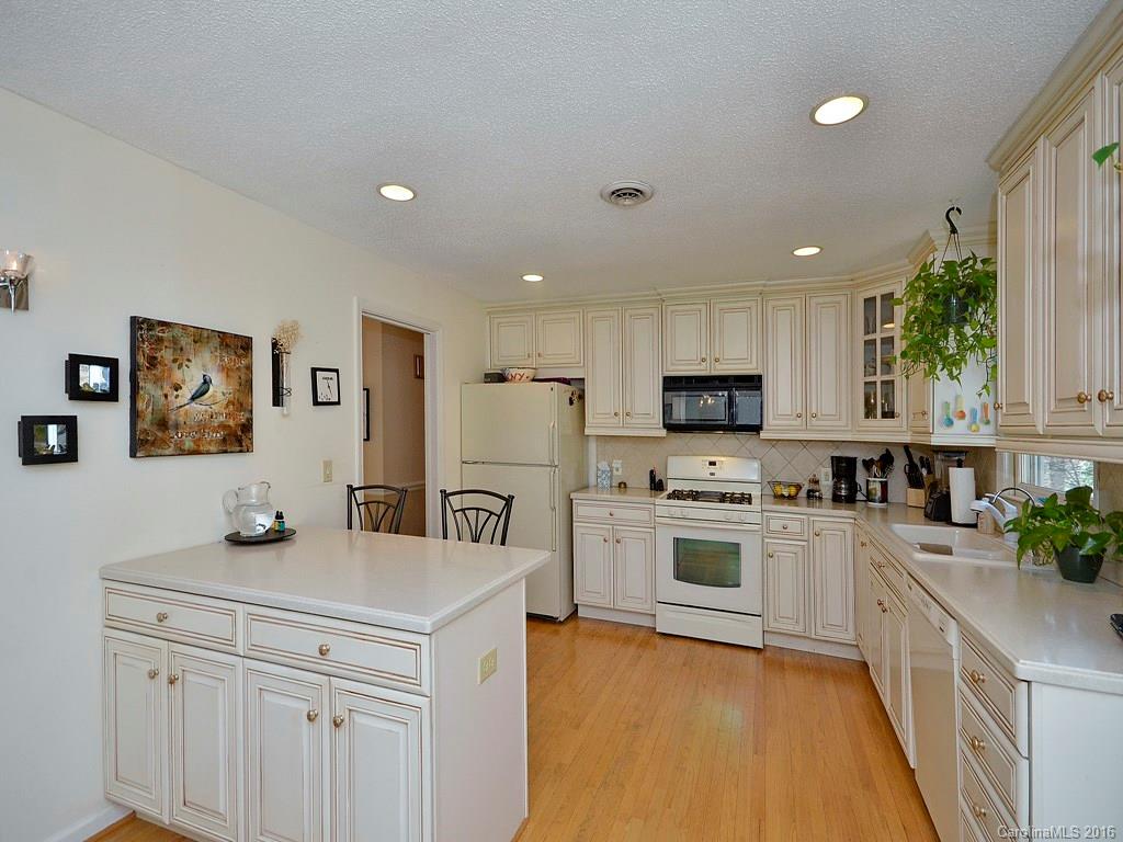 137 Brandon Road Hendersonville, NC 28739 - Photo 8 of 20 a kitchen with stainless steel appliances granite countertop a stove top oven a sink a refrigerator and white cabinets with wooden floor