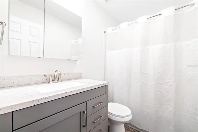 a bathroom with a granite countertop sink a toilet and a mirror